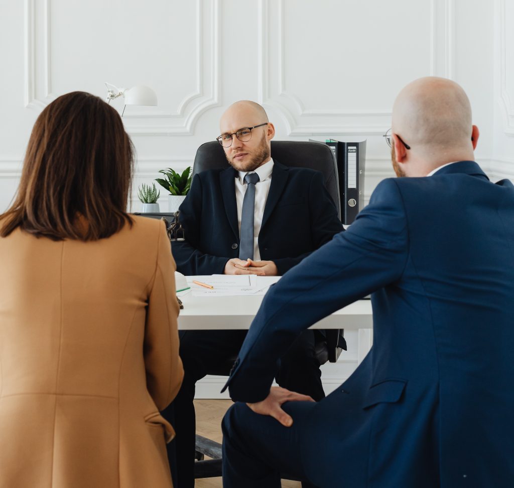 A man talking to two employees behind a desk