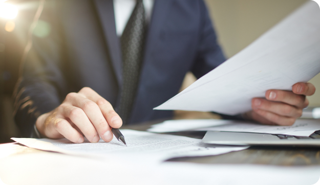 A man reading through a paper with a pen