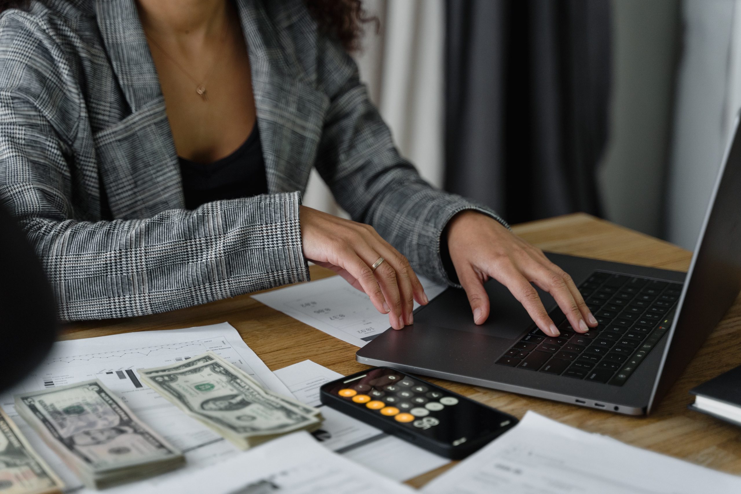 A woman on a computer with a calculator next to her